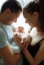 Woman and man holding on hands a newborn. On the background window. Mom, dad and baby. Portrait of young family. Happy family life Royalty Free Stock Photo