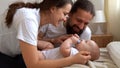 Woman And Man Holding Newborn. Mom, Dad And Baby On Bed. Close-up. Portrait of Young Smiling Family With Newborn On Royalty Free Stock Photo