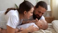 Woman And Man Holding Newborn. Mom, Dad And Baby On Bed. Close-up. Portrait of Young Smiling Family With Newborn On Royalty Free Stock Photo