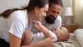 Woman And Man Holding Newborn. Mom, Dad And Baby On Bed. Close-up. Portrait of Young Smiling Family With Newborn On Royalty Free Stock Photo