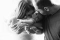 Woman and man holding a newborn. Mom, dad and baby. Close-up. Portrait of young smiling parents kissing their baby Royalty Free Stock Photo