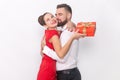 Woman and man hugging each other, female holding red present box, husband kissing his wife. Royalty Free Stock Photo