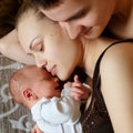 Woman and man lie on bed together with newborns. Mom, dad and baby. Boy clung to his mother. Portrait of young smiling family with Royalty Free Stock Photo