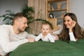 Woman and a man are lying on a bed with their baby son. Mom, Dad and baby, happy family at home Royalty Free Stock Photo