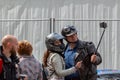 Happy and smiling woman and man motorcyclists in helmets take selfie using smartphone with a sliding monopod