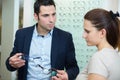 Woman and man in optician shop discussing price for glasses