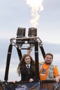 Woman and man (pilot) standing in the basket of a balloon, pilot regulating gas-burner