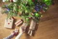 Woman and man putting hand made gift wrapping in a kraft paper under christmas tree. Presents for family. Top view. Flat lay. Royalty Free Stock Photo