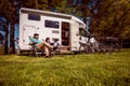 Woman with a man resting near motorhomes in nature. Family vacation travel, holiday trip in motorhome RV, Caravan car Vacation. Royalty Free Stock Photo