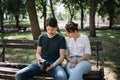 Woman and man sitting on bench and looking at camera display