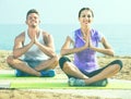 Woman and man sitting cross-legged do yoga poses on beach Royalty Free Stock Photo