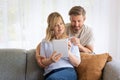 Woman and man sitting at home on the sofa and using touchpad Royalty Free Stock Photo