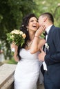 Woman and man smile on wedding day. Groom kiss happy bride with bouquet. Wedding couple in love. Newlywed couple on Royalty Free Stock Photo