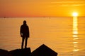 Woman or man standing on rock looking straight. Nature and beauty concept. Orange sundown. Girl silhuette at sunset