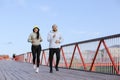 A woman and a man in sweatshirts run on the bridge in the morning workout