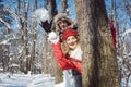 Woman and man in winter throwing snowball hiding behind a tree Royalty Free Stock Photo