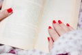 Woman manicured hand with red nails and book Royalty Free Stock Photo