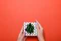 Woman manicured hands holding green gift box on dark orange background, copy space, top view, flat lay. Giving presents or Royalty Free Stock Photo