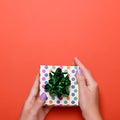 Woman manicured hands holding green gift box on dark orange background, copy space, top view, flat lay. Giving presents or Royalty Free Stock Photo