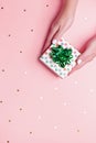 Woman manicured hands holding green giftbox on pastel pink background with confetti, copy space, top view, flat lay. Giving Royalty Free Stock Photo