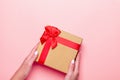 Woman manicured hands holding red and golden wrapped present or giftbox on pastel pink background, copy space, top view, flat lay Royalty Free Stock Photo