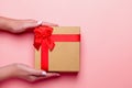 Woman manicured hands holding red and golden wrapped present or giftbox on pastel pink background, copy space, top view, flat lay Royalty Free Stock Photo