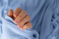 Woman manicured hands, stylish beige nails. Closeup of manicured nails of female hand in blue sweater in blue background Royalty Free Stock Photo