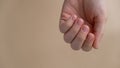 Woman manicured hands, stylish beige nails. Closeup of manicured nails of female hand in blue sweater on neutral beige Royalty Free Stock Photo