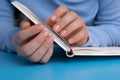 Woman manicured hands, stylish beige nails on paper notebook. Closeup of manicured nails of female hand in blue sweater Royalty Free Stock Photo