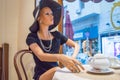 Woman mannequin in elegant hat and dress sitting at cafe table in window, Cagliari, Sardinia, Italy-October 09, 2018