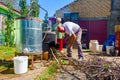 Woman is manually mixing fruit marc in distillation apparatus, man is throwing firewood for maintaining fire Royalty Free Stock Photo