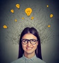 Woman with many ideas light bulbs above head looking up