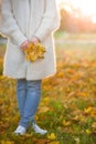 Woman with maple leaves on autumn sunset background. Girl walking in the park and enjoying sunny weather