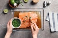 Woman marinating raw salmon in dish