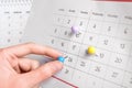 Woman marking date in calendar with drawing pin