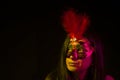 A woman in mask in a black background. Yellow and red light