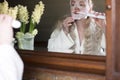 a woman in a mask brushing her teeth with an electric toothbrush Royalty Free Stock Photo