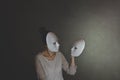 Woman with mask chooses another mask of herself, the concept of introspection Royalty Free Stock Photo