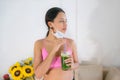 Woman with mask drinking green detoxifying shake after a training session Fitness