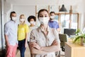 Woman in mask over creative team at office