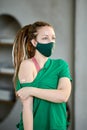 Woman in mask and with sticking-plaster on arm where vaccine was.