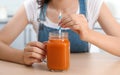 Woman with mason jar of tasty juice at table indoors, closeup