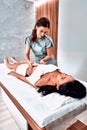 Woman massage therapist doing massage on the sides of a young girl in a massage parlor Royalty Free Stock Photo