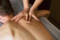 Woman massages under the shoulder blade on the back. Masseur does massage to a man lying on a couch
