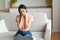 Woman Massaging Aching Neck Sitting On Sofa At Home