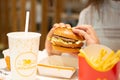 Woman with McDonald`s burger, French fries and drink at table in cafe, closeup