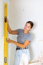 Woman measures deviations from predetermined vertical wall using building level