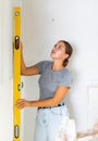 Woman measures deviations from predetermined vertical wall using building level