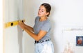 Woman measures deviations from predetermined vertical wall using building level