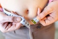 Woman measures her abdomen with a measuring tape